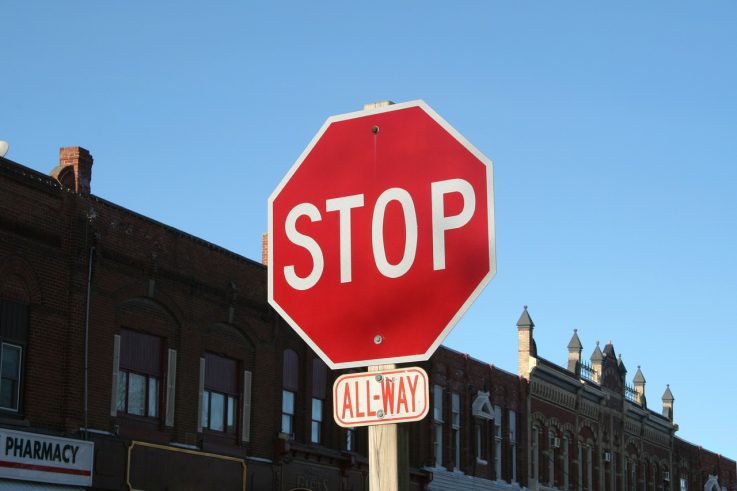 Red Stop Sign with blue sky and city background.
